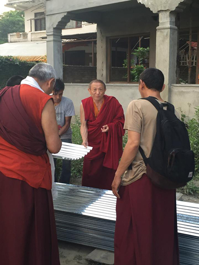 Chökyi Nyima Rinpoche bei der Inspektion der Wellblächer, die als Notfallunterkünfte vor dem Monsun verbaut werden.