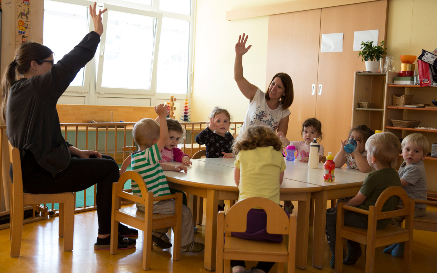 Kinderbetreuungsgruppe im Techno-Z: Betreuerinnen und Kinder sitzen um einen Tisch